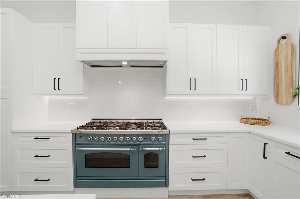 522 31st Street Southwest Naples, FL 34117 - Photo 16 of 38 Gourmet kitchen featuring a striking teal range, white shaker-style cabinetry, white countertops, a white subway tile backsplash, and dark hardware