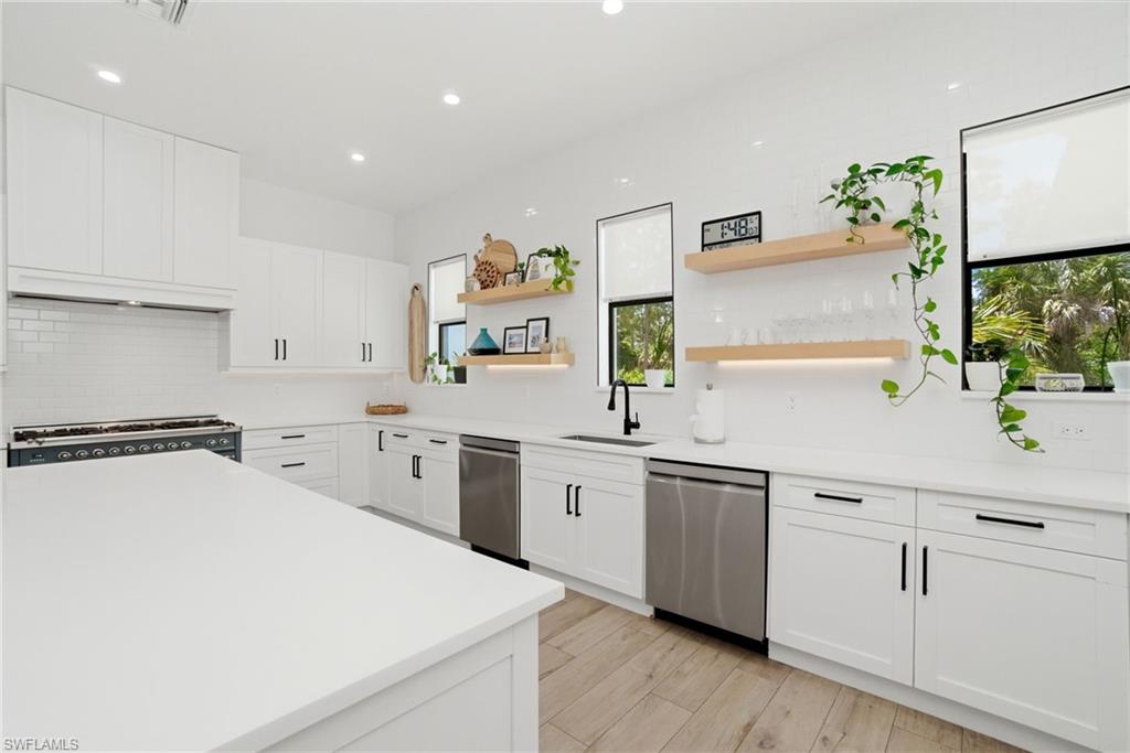 522 31st Street Southwest Naples, FL 34117 - Photo 17 of 38 Spacious kitchen featuring white cabinetry, light countertops, subway tile backsplash, stainless steel appliances, and wood-finish flooring