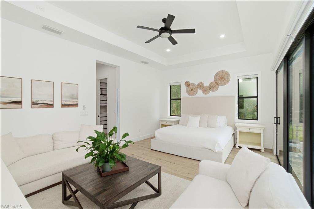 522 31st Street Southwest Naples, FL 34117 - Photo 18 of 38 Spacious bedroom featuring wood-finish flooring, a tray ceiling with a ceiling fan, recessed lighting, and large sliding glass doors