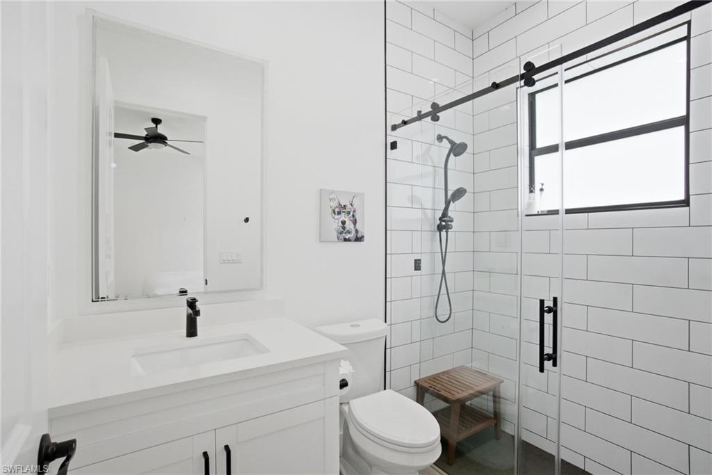 522 31st Street Southwest Naples, FL 34117 - Photo 25 of 38 Modern bathroom featuring a white vanity with integrated sink, black faucet, and a large wall-mounted mirror
