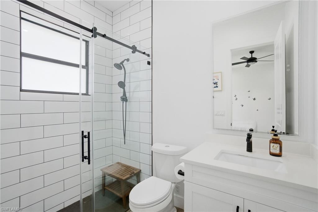 522 31st Street Southwest Naples, FL 34117 - Photo 29 of 38 White subway tile shower with a clear glass enclosure, matte black fixtures, and a window