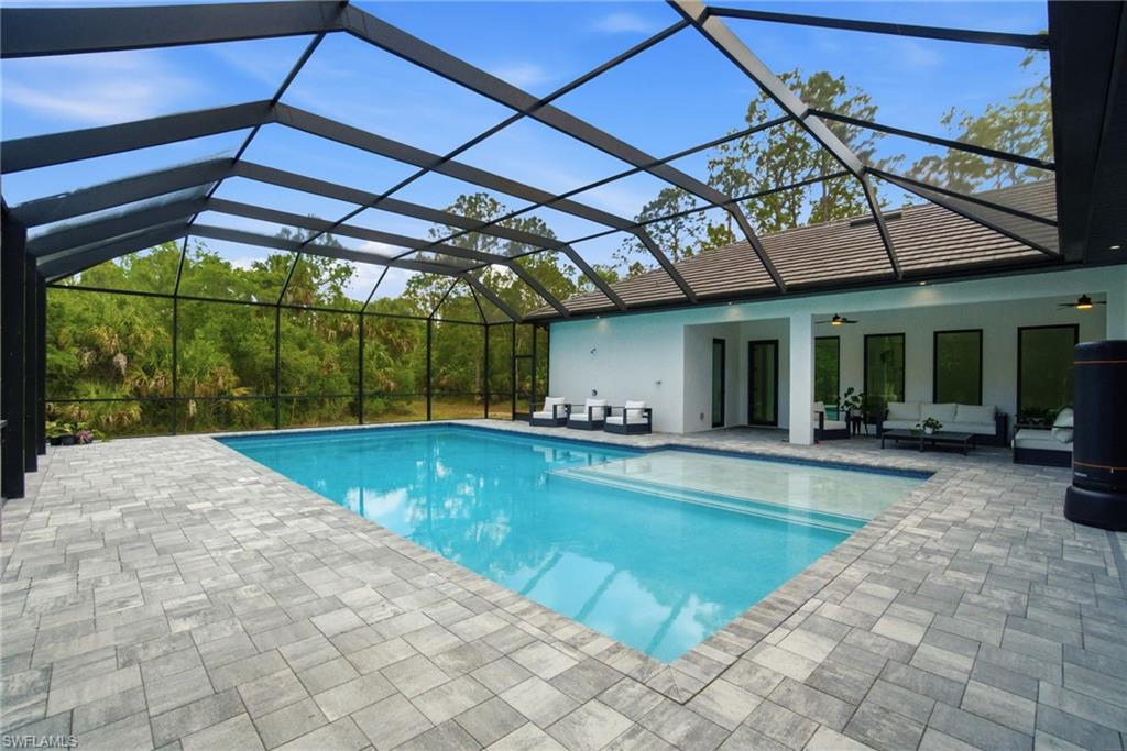522 31st Street Southwest Naples, FL 34117 - Photo 35 of 38 Screened enclosure featuring a rectangular swimming pool with integrated steps, surrounded by gray paver decking