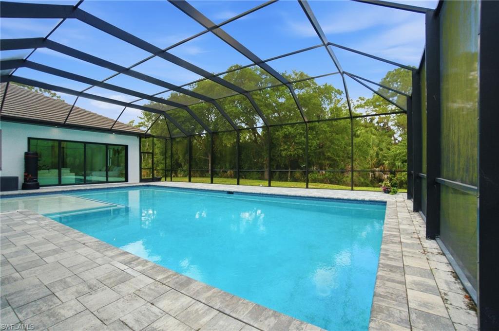 522 31st Street Southwest Naples, FL 34117 - Photo 36 of 38 Screened pool enclosure featuring a rectangular pool, integrated spa, and paver decking