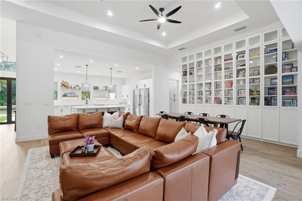 522 31st Street Southwest Naples, FL 34117 - Photo 10 of 38 Expansive living area with wood-finish flooring and a tray ceiling featuring a ceiling fan