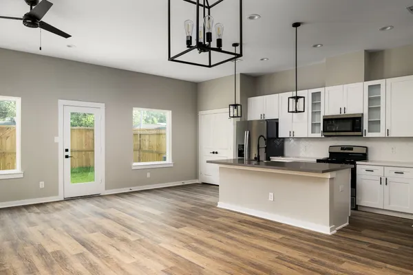 a kitchen with stainless steel appliances a stove top oven a sink a window and cabinets