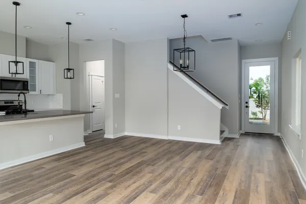 a view of empty room with wooden floor and kitchen view