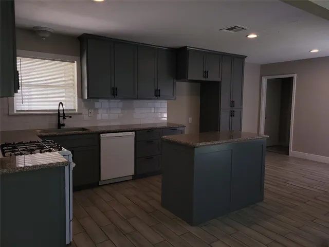 a kitchen with granite countertop wooden cabinets and a stove