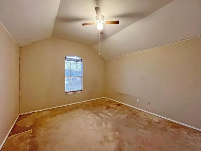 an empty room with a window and chandelier fan