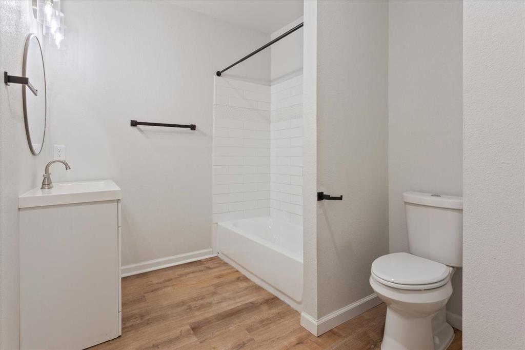 3109 North 20th Street Waco, TX 76708 - Photo 13 of 24 Bathroom featuring a white vanity with integrated sink, brushed nickel faucet, and wood-finish flooring
