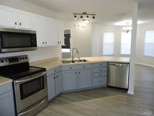 a kitchen with granite countertop white cabinets stainless steel appliances and a sink