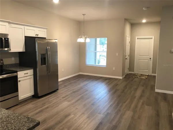 a view of a kitchen with wooden floor and electronic appliances