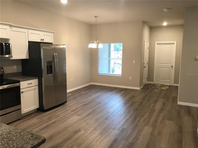a view of a kitchen with wooden floor and electronic appliances