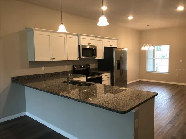 a kitchen with stainless steel appliances granite countertop a sink a microwave cabinets and wooden floor