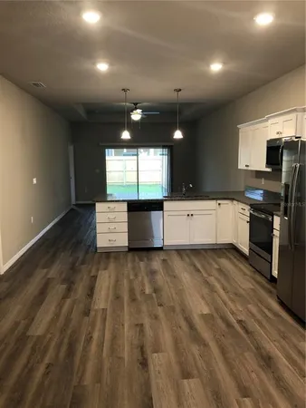 a large kitchen with stainless steel appliances a large counter top a stove and a refrigerator