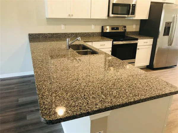 a kitchen with stainless steel appliances granite countertop a sink stove and microwave