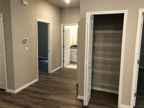 a view of a hallway with wooden floor and closet