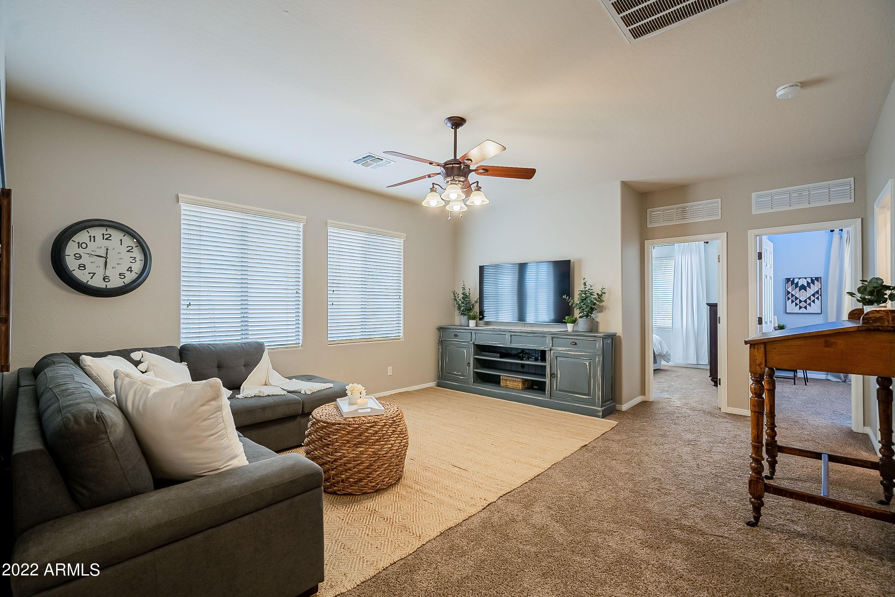 4770 East Buckboard Road Gilbert, AZ 85297 - Photo 58 of 97 a living room with furniture a clock and a flat screen tv