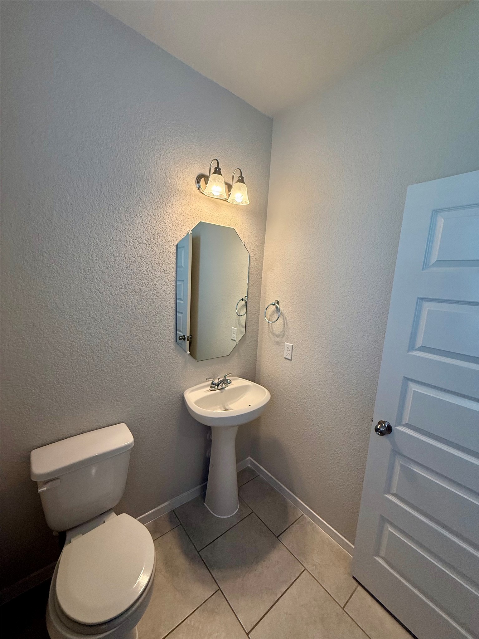 212 Lake Placid Run Elgin, TX 78621 - Photo 4 of 27 A compact and functional powder room with a pedestal sink and modern tile flooring.