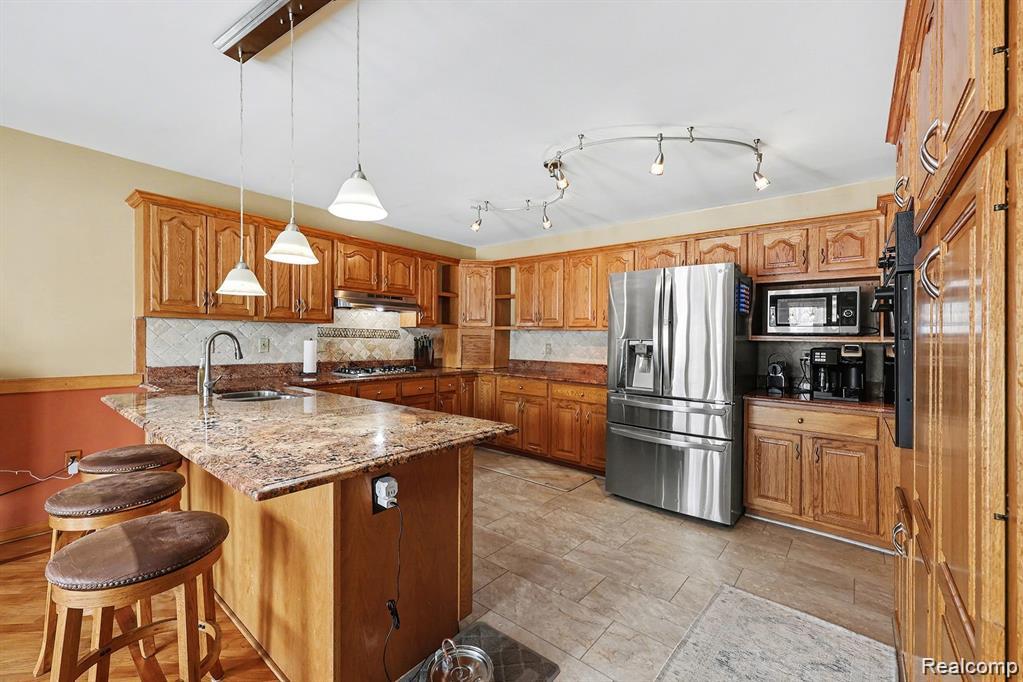 7277 Cardinal Road Algonac, MI 48001 - Photo 21 of 36 Kitchen featuring light stone counters, wood finish cabinets, a breakfast bar, and stainless steel appliances