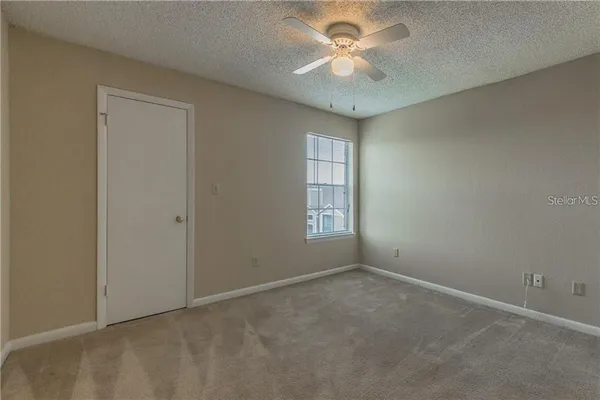 an empty room with windows and fan