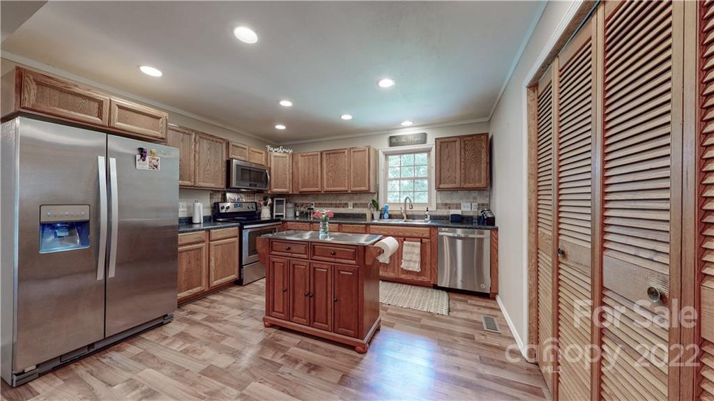6118 South Rocky River Road Monroe, NC 28112 - Photo 9 of 33 a kitchen with stainless steel appliances granite countertop a refrigerator a sink dishwasher a stove and white countertops with wooden floor