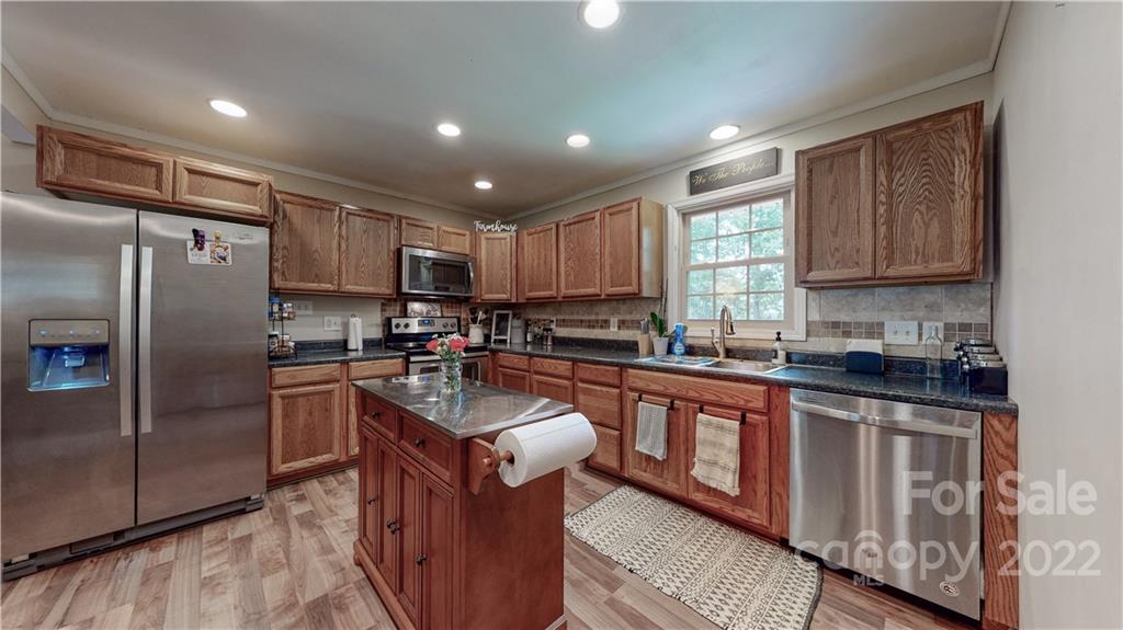 6118 South Rocky River Road Monroe, NC 28112 - Photo 10 of 33 a large kitchen with stainless steel appliances granite countertop a stove a sink dishwasher a refrigerator and a microwave oven