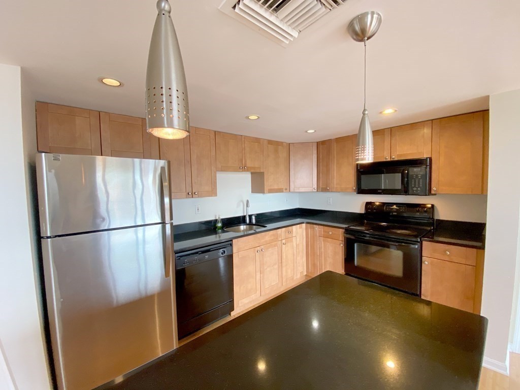 85 Brainerd Road, Unit 503 Boston, MA 02134 - Photo 2 of 21 a kitchen with granite countertop a refrigerator a sink a stove a microwave and island