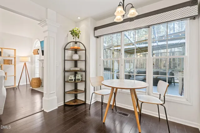 a dining room with wooden floor a chandelier a glass table and chairs