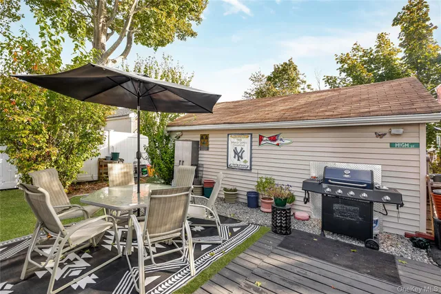 a view of a patio with table and chairs under an umbrella with a barbeque