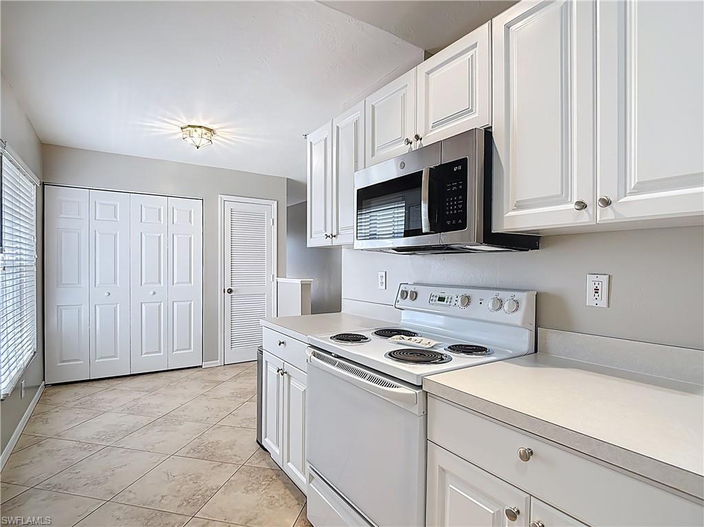 4970 Deerfield Way, Unit F203 Naples, FL 34110 - Photo 14 of 47 a kitchen with stainless steel appliances granite countertop a sink a stove a microwave and cabinets