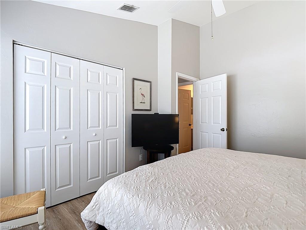 4970 Deerfield Way, Unit F203 Naples, FL 34110 - Photo 29 of 47 a bedroom with a bed and wooden floor