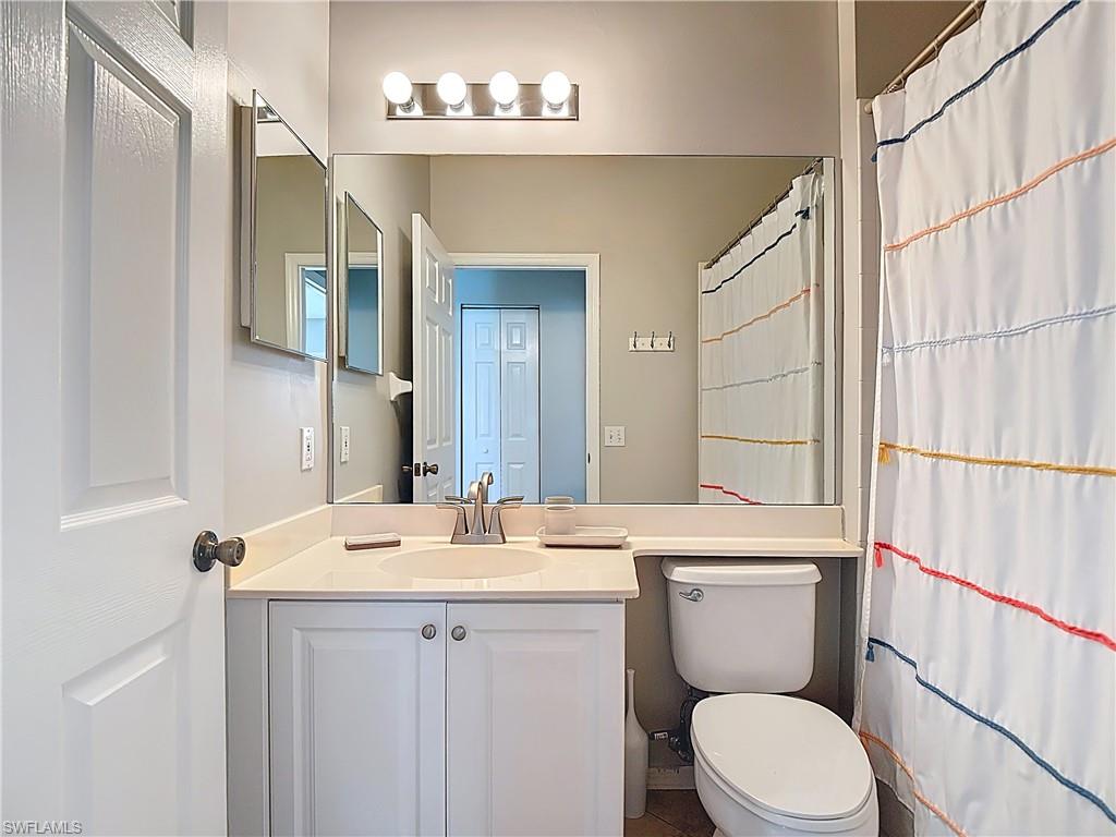 4970 Deerfield Way, Unit F203 Naples, FL 34110 - Photo 30 of 47 a bathroom with a toilet a sink a mirror and a shower