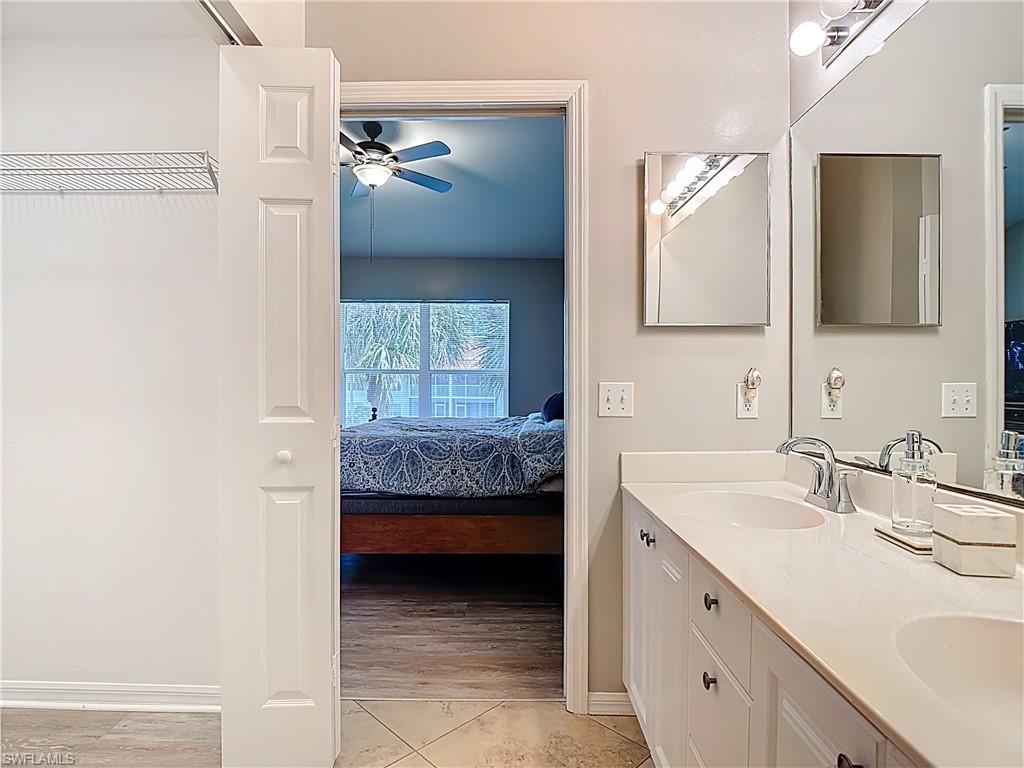 4970 Deerfield Way, Unit F203 Naples, FL 34110 - Photo 38 of 47 a en suite bathroom with a double vanity sink and a mirror