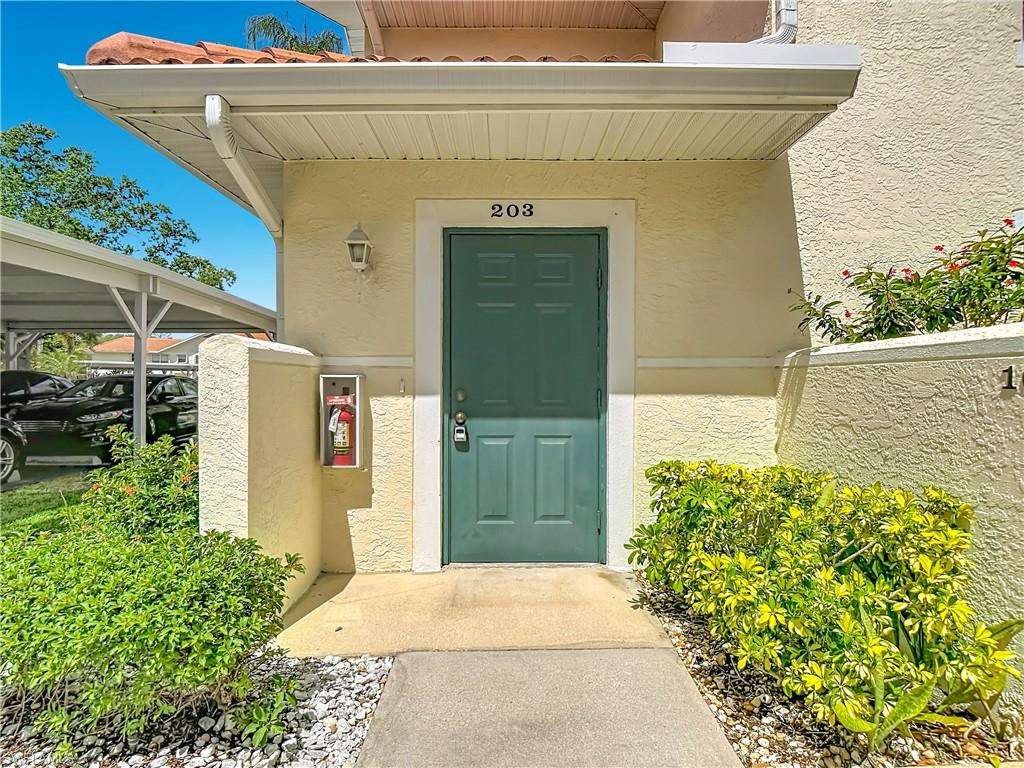 4970 Deerfield Way, Unit F203 Naples, FL 34110 - Photo 5 of 47 a front view of a house with a yard