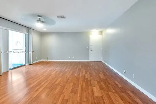 a view of empty room with wooden floor and fan