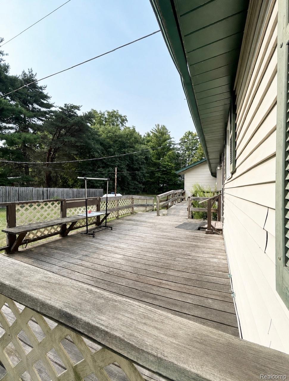 140 Larson Road Attica, MI 48412 - Photo 39 of 41 Expansive wood deck with lattice railing, integrated bench seating, and an accessibility ramp leading to the residence