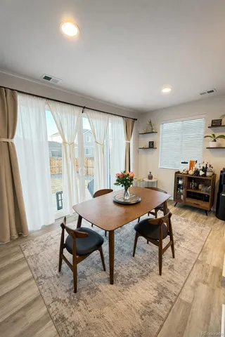 a kitchen with a refrigerator a stove a sink a dining table and chairs with wooden floor