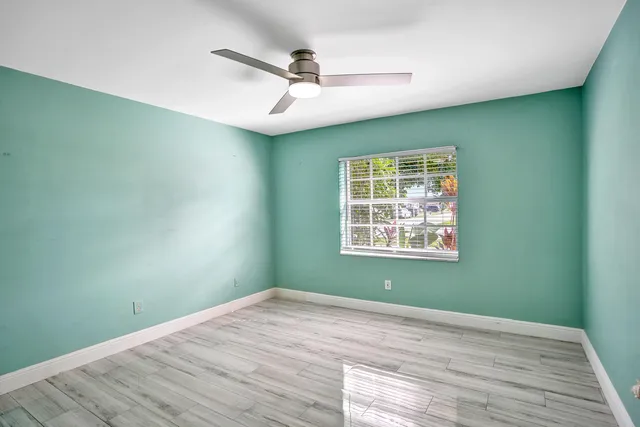 en empty room with wooden floor ceiling fan and window