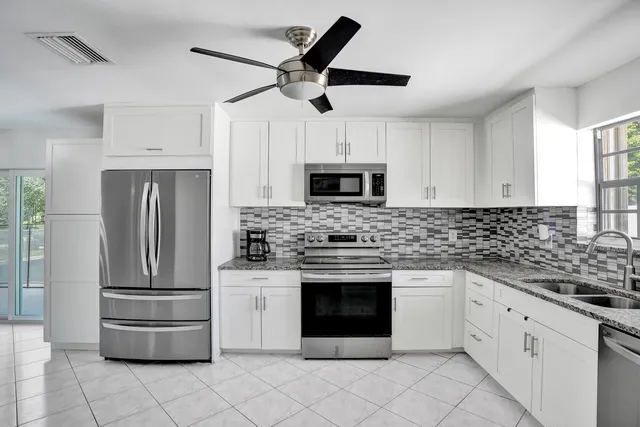 a kitchen with stainless steel appliances granite countertop a refrigerator a stove a microwave oven with white cabinets