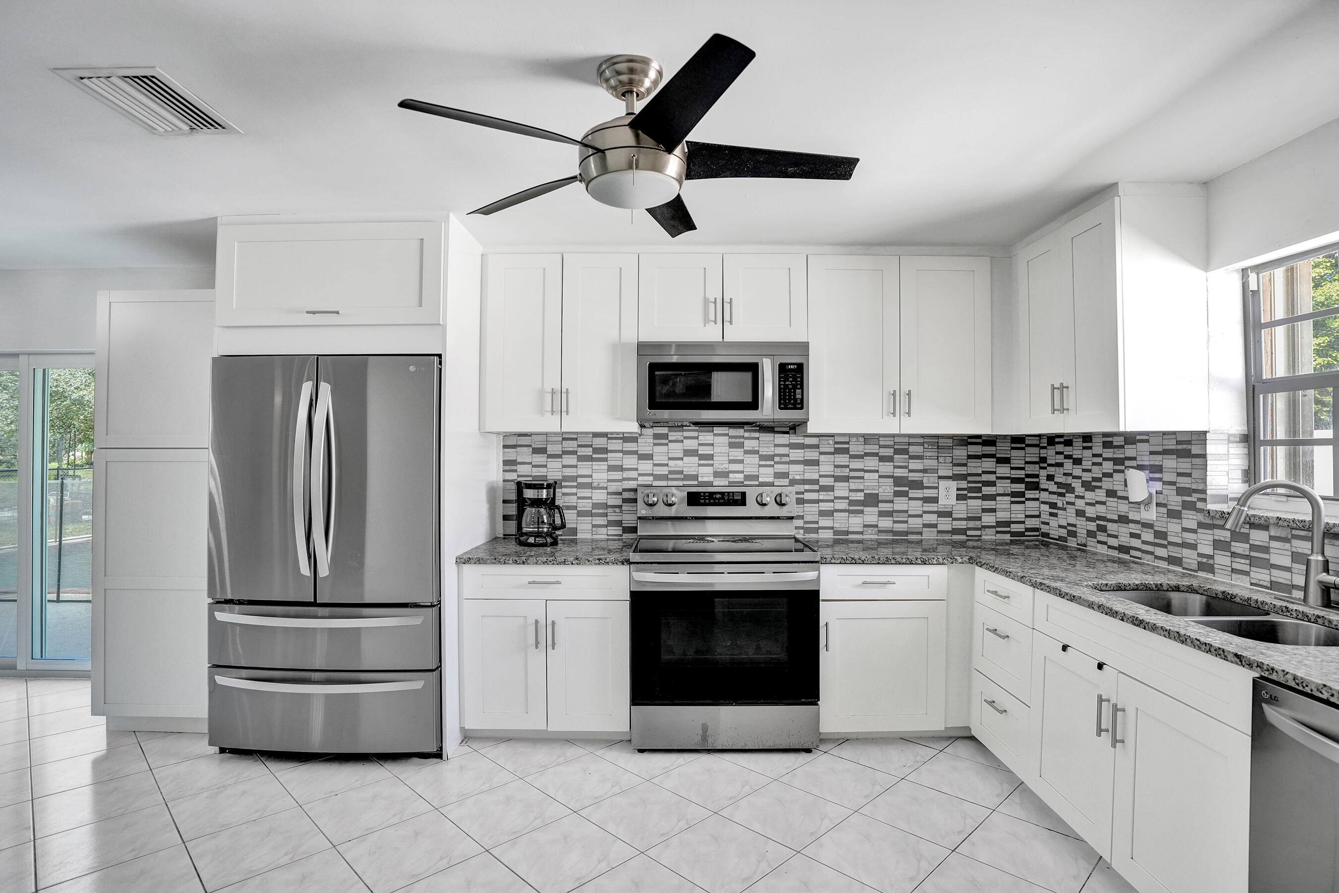 22335 Boulder Street Boca Raton, FL 33428 - Photo 9 of 36 a kitchen with stainless steel appliances granite countertop a refrigerator a stove a microwave oven with white cabinets