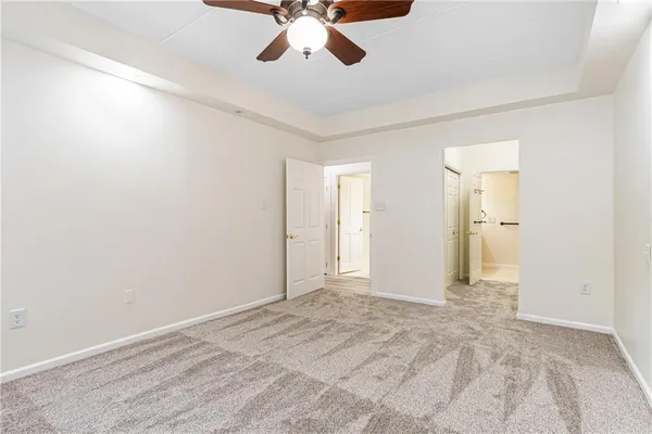 an empty room with a chandelier fan and windows