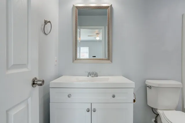 a bathroom with a toilet sink vanity and mirror