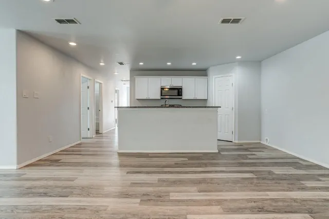 a view of kitchen with kitchen island a sink wooden floor and a refrigerator