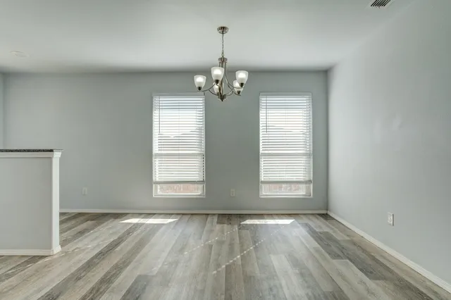 an empty room with wooden floor exposed radiator and windows