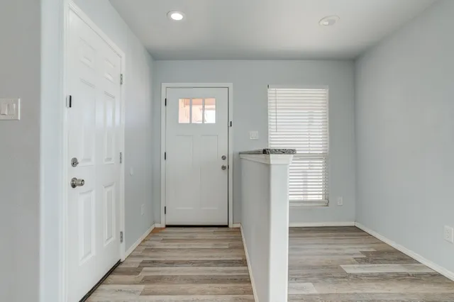 a view of a hallway with wooden floor and a bathroom