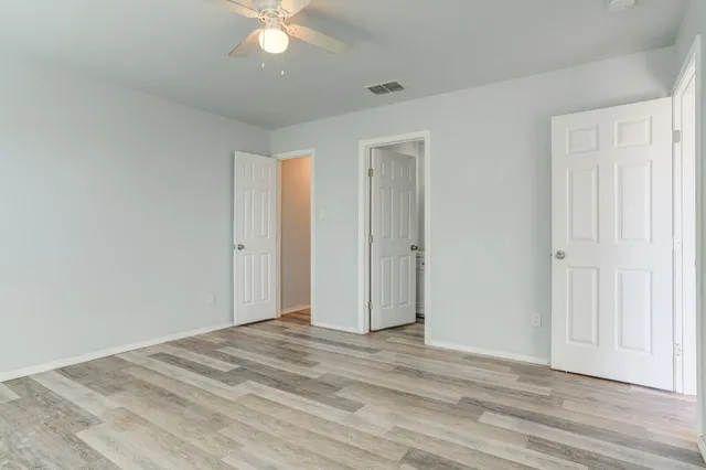 a view of a room with wooden floor and ceiling fan