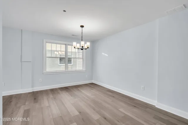 a view of empty room with wooden floor fan and window