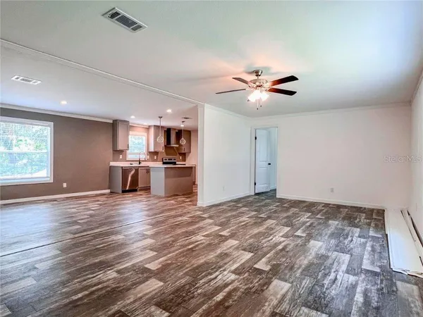 a view of kitchen and empty room with a ceiling fan