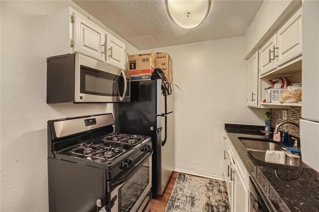 2401 Manor Road, Unit 111 Austin, TX 78722 - Photo 6 of 23 a kitchen with stainless steel appliances granite countertop a stove and a microwave