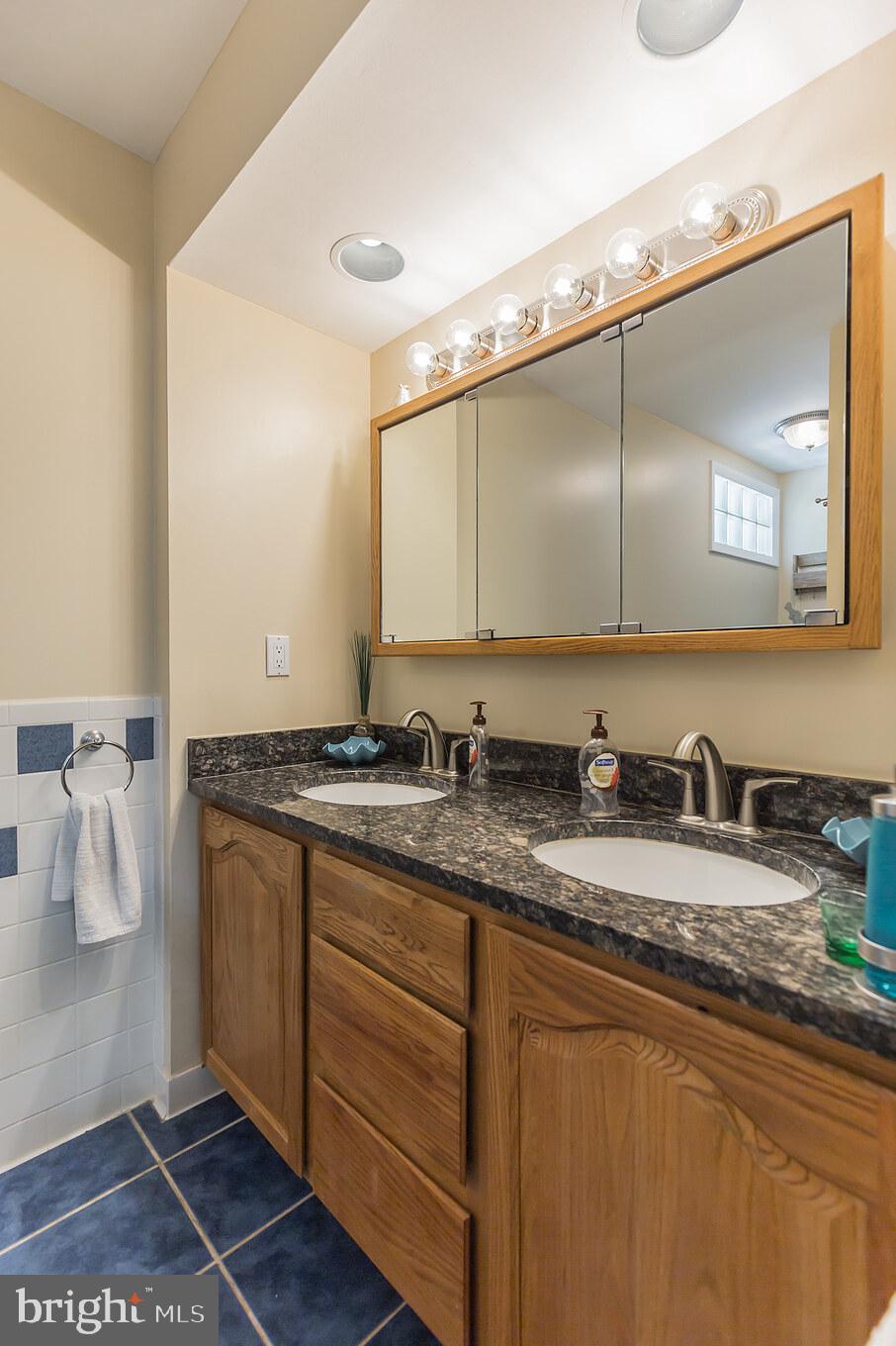 7020 Hadlow Drive Springfield, VA 22152 - Photo 23 of 29 a bathroom with a granite countertop sink and a mirror